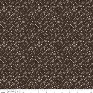 May include: Brown fabric with a repeating pattern of interlocking circles and small dots. The design is in a light beige color, creating a contrast against the dark brown background. The fabric is measured in inches.