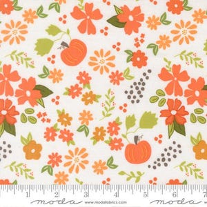 May include: A white fabric featuring a repeating pattern of orange pumpkins, orange flowers, and green leaves. A ruler at the bottom shows the fabric width in inches, with the text moda and www.modafabrics.com printed along the edge.