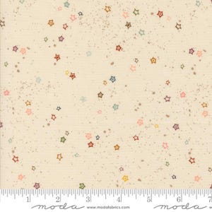 May include: Cream-colored fabric patterned with scattered, colorful star shapes in shades of red, pink, green, blue, and yellow. The fabric also features small, brown speckles. A ruler is at the bottom of the image.