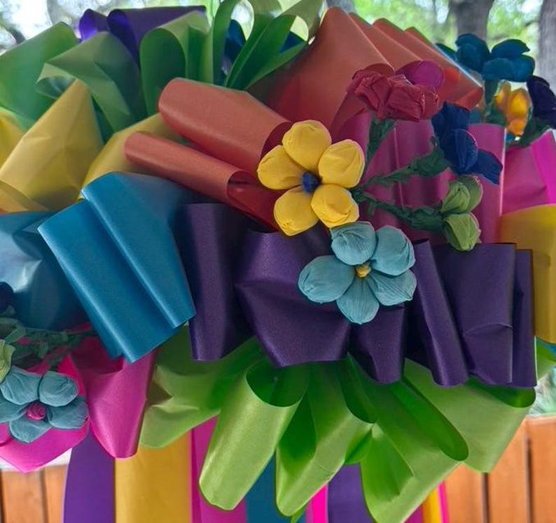 Op de afbeelding: Een kleurrijk papieren bloemenarrangement met fel roze, blauwe, groene, gele en paarse linten. De bloemen zijn van papier en hebben een 3D-effect.