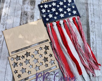 May include: A patriotic wooden wall hanging with a blue star-studded top, red and white fabric streamers, and a wooden star cutout. Includes a separate wooden rectangle and a wooden rectangle with star cutouts. The text "RB Crazy Designs" is visible.