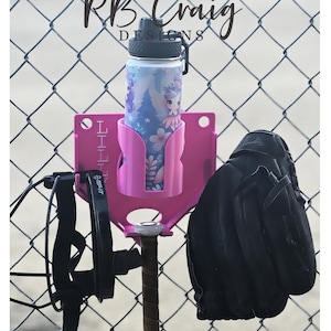 May include: A pink baseball-themed water bottle holder with a water bottle featuring a fairy design. A black baseball glove and a black strap are also visible. The holder is attached to a baseball bat.