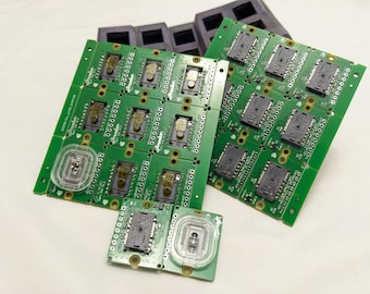May include: Multiple green circuit boards with black components and a white label that says "Promoter". The boards are stacked on top of each other. There are also two smaller green circuit boards with a clear plastic circle in the center.