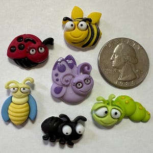 May include: Six colorful plastic insect buttons with googly eyes. The insects include a ladybug, a butterfly, a bee, a caterpillar, an ant, and a bee.
