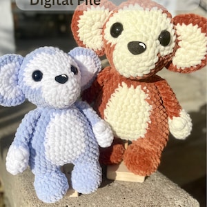 May include: Two crocheted plush toys, one brown and white and one blue and white. The brown and white toy has a monkey-like face and the blue and white toy has a bear-like face. Both toys are standing on a wooden surface. Crochet Pattern Digital File.