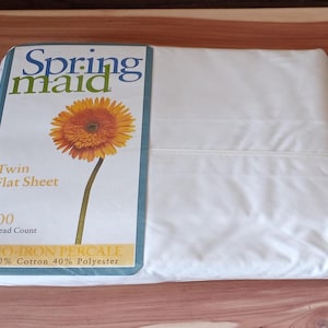 May include: A white twin flat sheet in plastic packaging with a label reading Springmaid, Twin Flat Sheet, 200 Thread Count, NO-IRON PERCALE, 60% Cotton 40% Polyester, featuring an illustration of an orange gerbera daisy flower.
