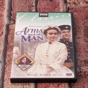 May include: DVD of "Arms and the Man" starring Helena Bonham Carter. The cover features a photo of the actors and the title in a stylized font. The DVD case is black and has the BBC Video logo.