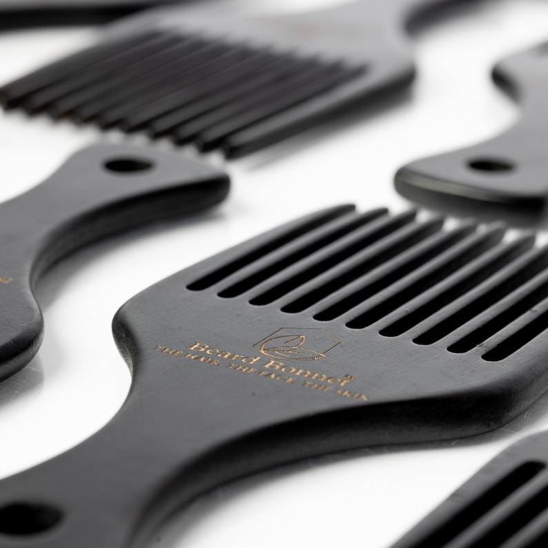 Pode incluir: Um conjunto de quatro pentes de madeira preta com um design de dentes largos. Os pentes t&ecirc;m uma pega arredondada e o texto "Beard Bonnet" est&aacute; gravado em um dos pentes.