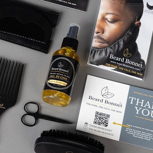 Pode incluir: Um gorro de barba preto, um pente preto, um par de tesouras pretas, uma escova de barba preta e uma garrafa de vidro transparente com um r&oacute;tulo preto que diz "Beard Bonnet All in One Scalp & Beard Oil" sobre uma superf&iacute;cie branca. O r&oacute;tulo tamb&eacute;m inclui o texto "www.beardbonnets.com The Hair. The Face. The Skin."