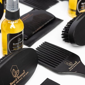 Pode incluir: Um conjunto de produtos para o cuidado da barba que inclui um pente de madeira preto, uma escova preta, um pente preto com cabo e uma garrafa de vidro transparente com tampa preta e um r&oacute;tulo dourado que diz "Beard Bonnet".