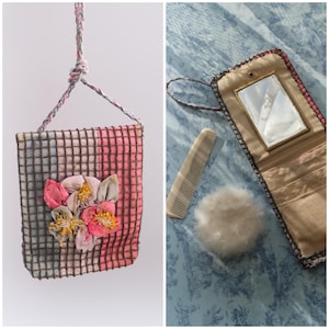 May include: A vintage-style handbag with a floral embellishment and a matching cord strap. The bag features a pink and gray grid pattern. A matching compact with a mirror, comb, and powder puff are also shown.