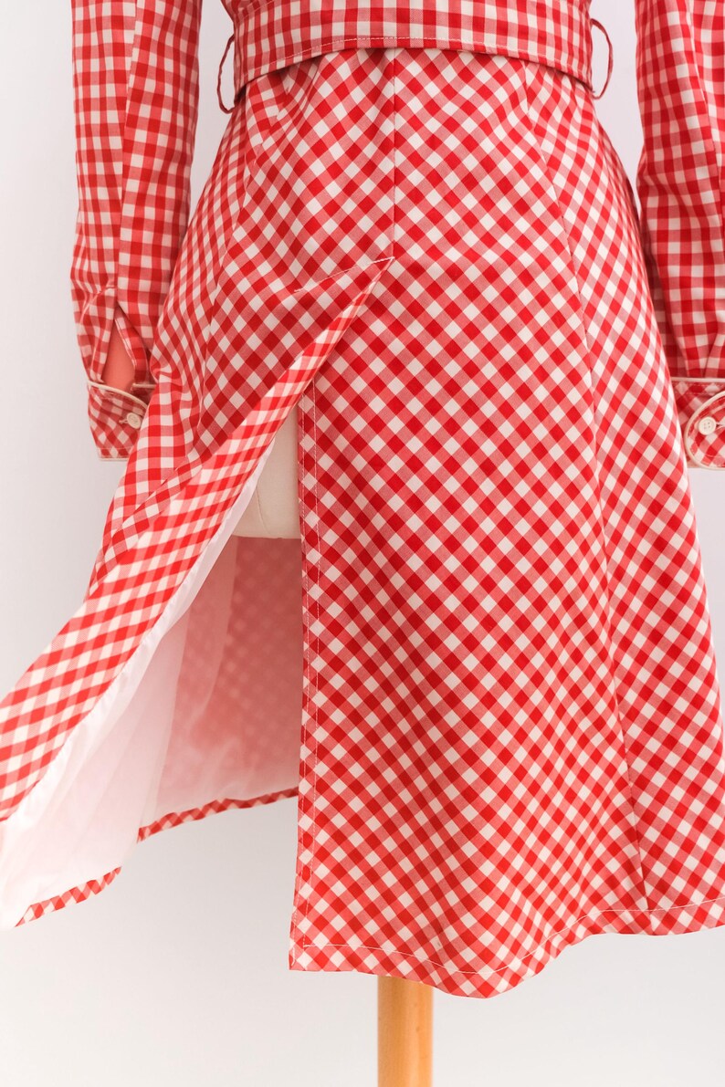 May include: A red and white gingham dress with a long sleeve and a belt. The dress has a white lining and a center back vent.