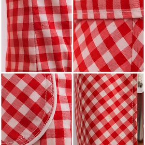 May include: Red and white gingham fabric with a white trim. The fabric has a checkered pattern.