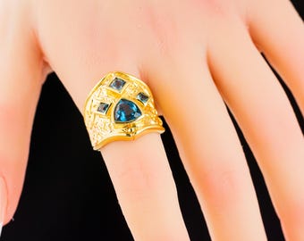 May include: A gold ring with a blue gemstone and smaller blue gemstones set in the band.