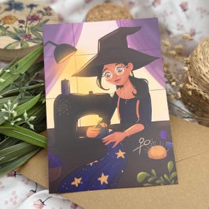 May include: A rectangular art print featuring a digital illustration of a person wearing a black witch hat and round glasses, sitting at a black sewing machine. The person is sewing a dark blue fabric with yellow star patterns. Scissors and a pin cushion are visible.