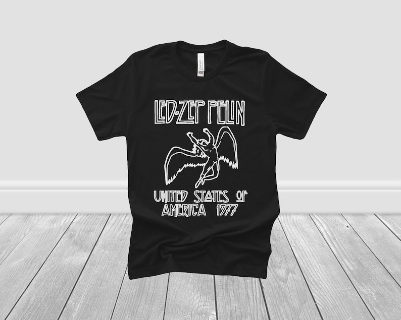 K&ouml;nnte beinhalten: Schwarzes T-Shirt mit einer wei&szlig;en Grafik einer gefl&uuml;gelten Figur und dem Text "LED-ZEP PELIN UNITED STATES of AMERICA 1977".