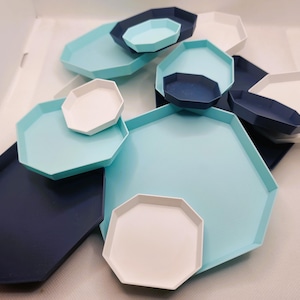 May include: A set of octagonal trays in various sizes, featuring a combination of light blue and dark blue colours. The trays are arranged in a decorative pattern, showcasing their unique shape and colour scheme.