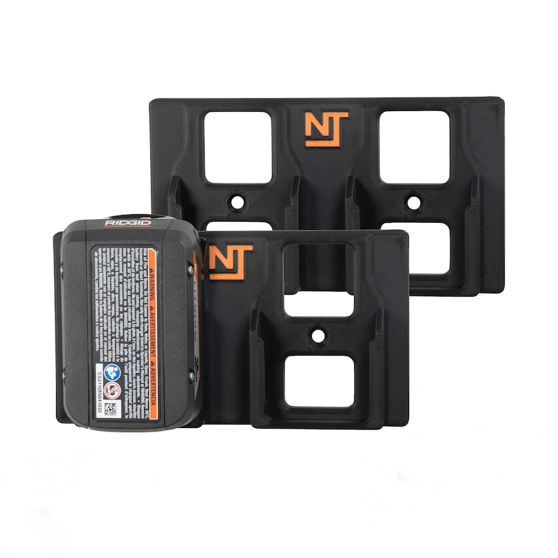 Op de afbeelding: Twee zwarte wandbeugels met de letters NT in oranje gedrukt. De beugels zijn ontworpen om twee Ridgid 18V-batterijen te houden. E&eacute;n beugel heeft een batterij.
