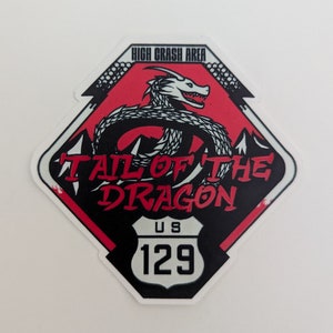 May include: A red and black diamond-shaped sticker with a white dragon illustration. The sticker says "Tail of the Dragon" and "High Crash Area" with a US Route 129 sign.