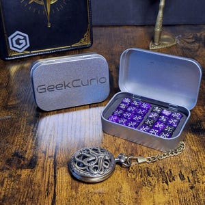 May include: A silver metal tin with the text GeekCurio embossed on the lid, containing a set of purple and black dice with numerical fractions. A round, ornate silver-toned metal pocket watch with an octopus design is attached to a chain.