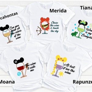 May include: Five white t-shirts with different Disney princess characters and wine glasses. The shirts feature the text "Pocahontas", "Merida", "Tiana", "Moana", and "Rapunzel". Each shirt has a different quote about wine.
