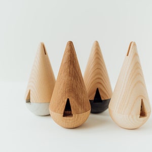 May include: Four wooden cone-shaped incense holders with different colored bases. The holders are made of light wood with a natural finish. The bases are gray, black, and natural wood.