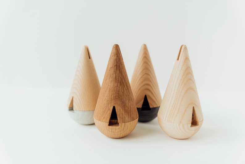 May include: Four wooden cone-shaped incense holders with different colored bases. The holders are made of light wood with a natural finish. The bases are gray, black, and natural wood.