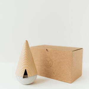 May include: A wooden and concrete incense burner in the shape of a cone. The burner is sitting on a brown cardboard box with the word "YOUND" printed on it.