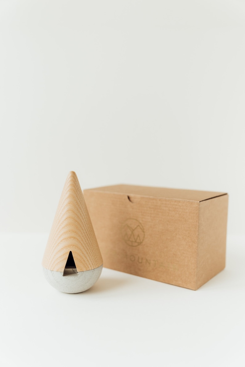 May include: A wooden and concrete incense burner in the shape of a cone. The burner is sitting on a brown cardboard box with the word "YOUND" printed on it.