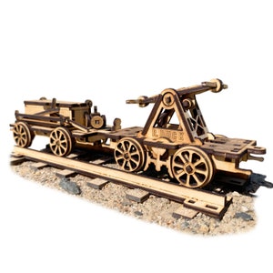 May include: A wooden model train with a crane on the back. The train is on a track and the crane is raised. The train is made of wood and has a brown finish. The crane is labeled "R.DUCK".