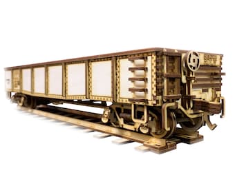 May include: A wooden model of a freight train car with a white painted cargo bed and the text "605200 RIDLEY" on the side. The model is on a wooden track.
