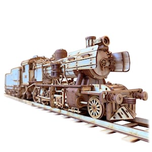 May include: A detailed wooden model of a vintage steam train, featuring intricate cut-out designs. The train is brown and light blue, with visible wheels, a smokestack, and a tender car. It sits on a light blue track, showcasing the craftsmanship of the model.
