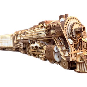 May include: A detailed wooden model of a steam locomotive train featuring intricate laser-cut parts, visible gears, and wheels. The front of the engine displays the number 5405 and a small plaque reading R. DUCK, with a connected tender car behind it.