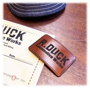 May include: A brown leather patch with black text that reads "R.DUCK Locomotive Works".