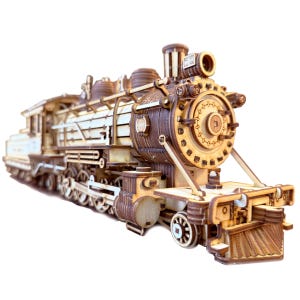 Könnte beinhalten: Ein Holzmodell einer alten Dampflokomotive mit filigranen Details, darunter Räder, Zahnräder und ein Schornstein. Das Modell ist aus Naturholz gefertigt und hat eine braune und weiße Farbgebung.