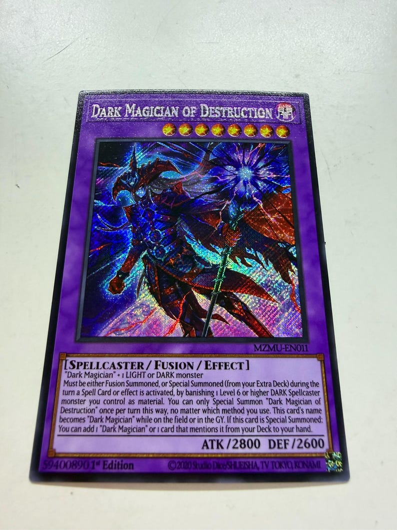 May include: A holographic trading card featuring "Dark Magician of Destruction" with a purple border. The card displays a detailed illustration of a dark wizard. Text includes card type, monster attributes, and attack/defense stats.