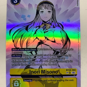 Może przedstawiać: Holograficzna karta kolekcjonerska Digimon z Inori Misono. Karta ma tęczowe tło foliowe i zawiera tekst opisujący efekty karty. Karta ma również numer 3 i słowo "Tamer".