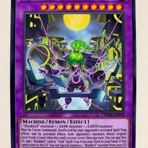 Puede incluir: Una carta coleccionable con el título "El Shaddoll Meshahrail" con un marco morado. La carta muestra un personaje de pelo verde con un atuendo morado, ambientado en un paisaje urbano futurista y una luna llena. El texto de la carta incluye detalles del juego.