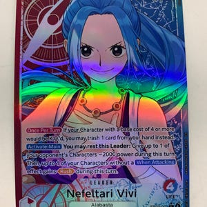 Puede incluir: Carta coleccionable holográfica con Nefeltari Vivi de Alabasta. La carta tiene un brillo vibrante, similar al arcoíris, e incluye detalles del personaje, texto del juego y una potencia de 5000. Está marcada como carta Líder.