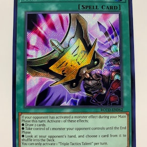Peut inclure: Une carte violette et dorée avec une finition holographique. La carte est du jeu de cartes à collectionner Yu-Gi-Oh! et présente le texte "Triple Tactics Talent" et "[SPELL CARD]" en blanc. Le numéro de la carte "ROTD-EN062" est imprimé dans le coin inférieur droit. Le texte de la carte décrit les effets de la carte, qui peuvent être activés pendant votre phase principale si votre adversaire a activé un effet de monstre. Le texte de la carte comprend également le texte "Vous ne pouvez activer "Triple Tactics Talent" qu'une fois par tour."