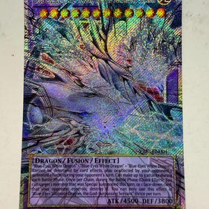 Może przedstawiać: Holograficzna karta kolekcjonerska zatytułowana Blue-Eyes Ultimate Dragon, the God-Surpassing Servant. Karta zawiera ilustrację wielogłowego smoka, dwanaście żółtych gwiazdek poziomu oraz tekst Dragon/Fusion/Effect z 4500 ATK i 3800 DEF.