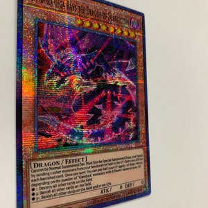 Peut inclure: Une carte de jeu de commerce holographique repr&eacute;sentant un dragon rouge, noir et bleu aux yeux brillants. La carte est intitul&eacute;e "Gandora Giga Rays the Dragon of Destruction" et porte le texte "DRAGON/EFFECT" dans le coin inf&eacute;rieur droit. La carte est issue du jeu de cartes &agrave; collectionner "Yu-Gi-Oh!"