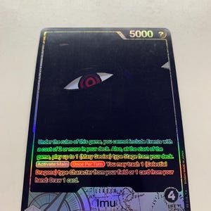 Puede incluir: Una tarjeta coleccionable negra con un diseño de ojo rojo y blanco. La tarjeta muestra el número 5000 y texto en inglés. Es una carta de tipo "Mary Geoise" con el texto "Imu" y "Leader".