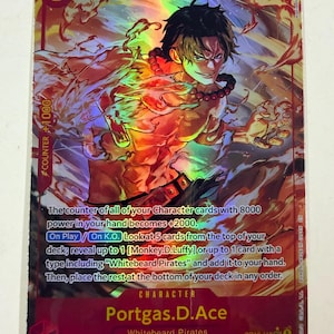 May include: A holographic One Piece trading card featuring Portgas D. Ace with a power level of 6000 and a cost of 5. The card displays a dynamic illustration of the character surrounded by flames, with detailed game text and the Whitebeard Pirates label.