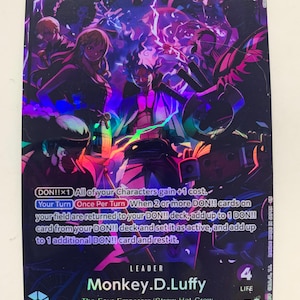 May include: A trading card featuring Monkey D. Luffy from the Four Emperors/Straw Hat Crew. The card has a purple and black background with multiple characters. The text includes "5000", "Strike", and card details.