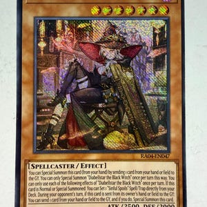 May include: A holographic Yu-Gi-Oh! trading card titled Diabellstar the Black Witch, featuring a character in a wide-brimmed hat and dark attire sitting on a chair. The card includes text detailing its spellcaster effect, 2500 ATK, and 2000 DEF.