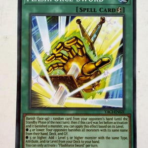 Może przedstawiać: Zielona karta kolekcjonerska Yu-Gi-Oh! o tytule Flashforce Sword, karta zaklęcia przedstawiająca złotą mechaniczną dłoń trzymającą miecz pośród jasnych promieni światła. Tekst na karcie opisuje mechanikę gry dotyczącą banowania i wyszukiwania.