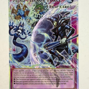 Peut inclure: Une carte à collectionner Yu-Gi-Oh! holographique intitulée Mind Mirror Force. La carte représente une silhouette en armure sombre, une créature bleue et un personnage vert dans un champ d'énergie violet et bleu. Texte incluant Trap Card, UT01-EN002.