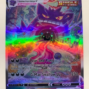 May include: A holographic Gengar VMAX Pokémon card. The card features a large purple Gengar character with a menacing grin. The card has the text "Gengar VMAX" and "Gigantamax". The card also has the text "Fear and Panic" and "G-Max Swallow Up".