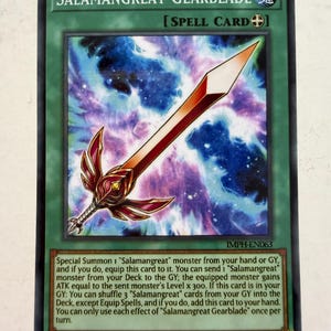Puede incluir: Una carta coleccionable de Yu-Gi-Oh! titulada Salamangreat Gearblade, una carta mágica verde con una ilustración de una espada roja y dorada sobre un fondo de nebulosa azul y morada, con texto de juego y el código IMPH-EN063 impreso debajo.